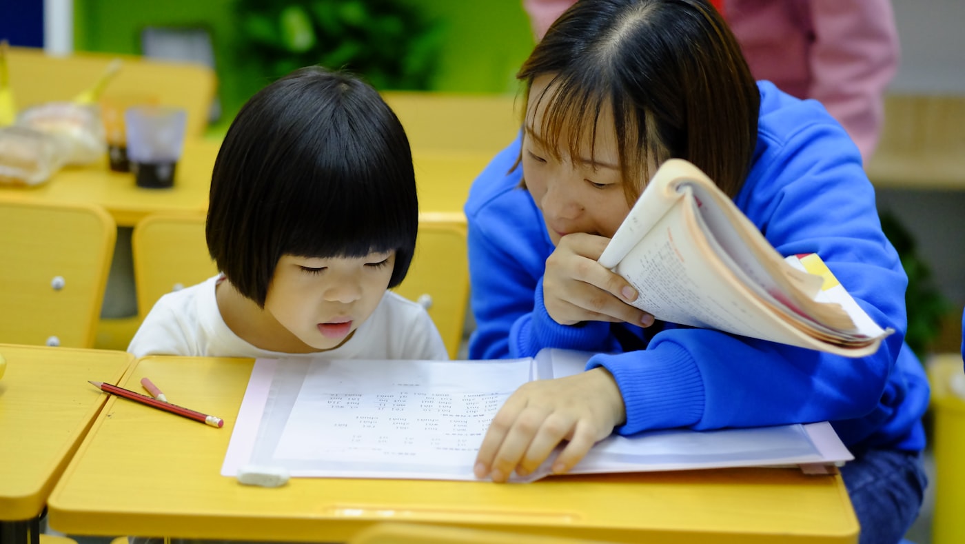 A mother and daughter working together at a desk, smiling